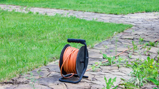Prodlužovací kabel na bubnu umístěný na zahradě